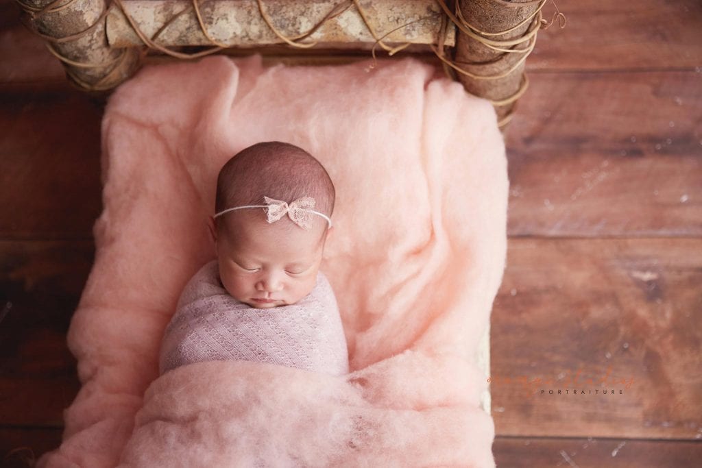 15 days old baby girl on log bed newborn portraits in singapore studio