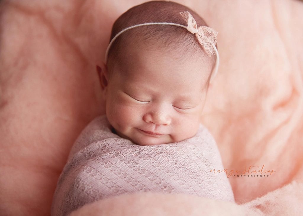 15 days old baby girl with dimple on log bed newborn portraits in singapore studio