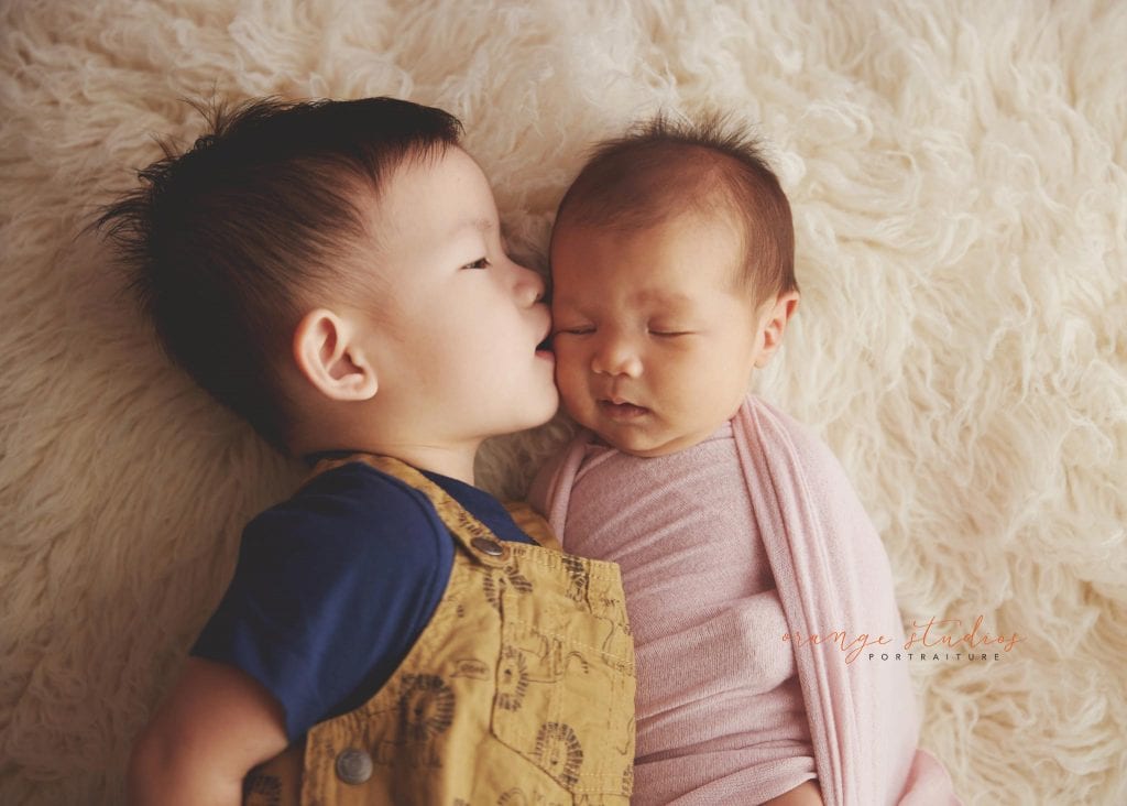 4 weeks old baby girl newborn portraits with elder brother kissing in singapore studio