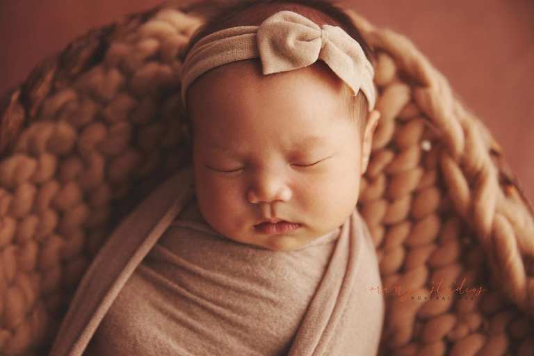4 weeks old baby girl newborn portraits in rattan basket in singapore studio