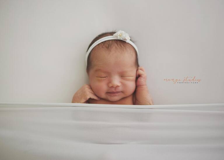 Sleeping newborn wrapped in white blanket during studio photoshoot in Singapore