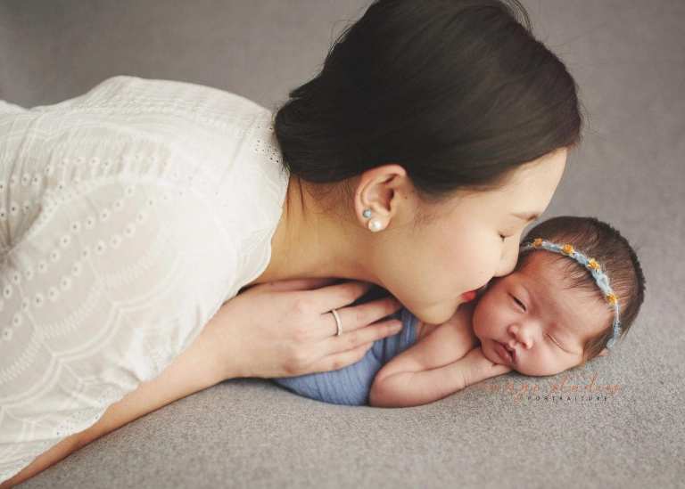 mum kissing 2 weeks old baby girl newborn portraits in singapore studio
