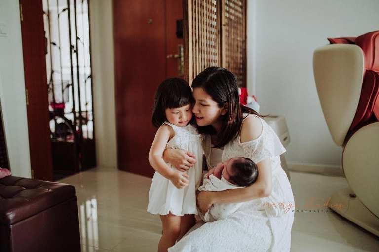 mummy hugging elder daughter during fresh 48 photoshoot at home