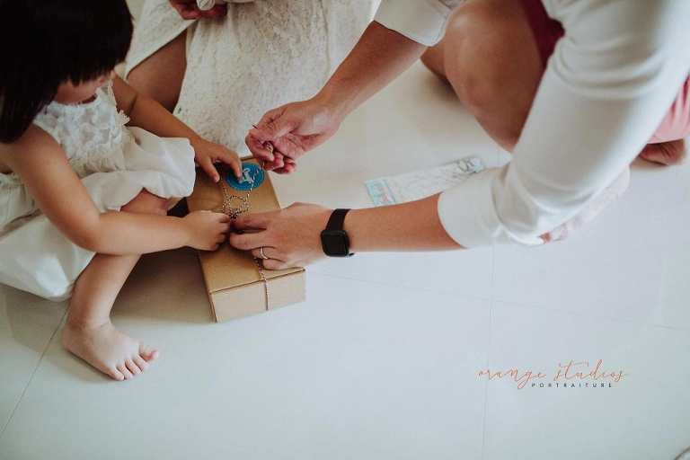 elder sister unwrapping gift from younger sister during fresh 48 photoshoot at home