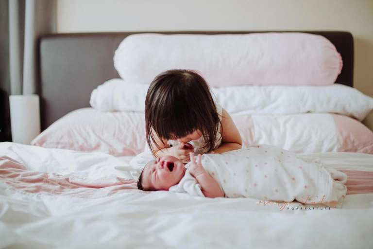 elder sister comforting baby sister during fresh 48 photoshoot at home