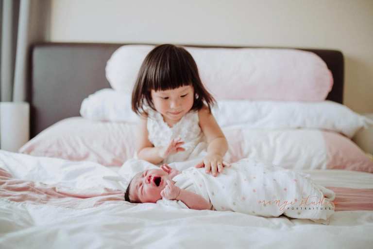 newborn baby with elder sister during fresh 48 photoshoot at home