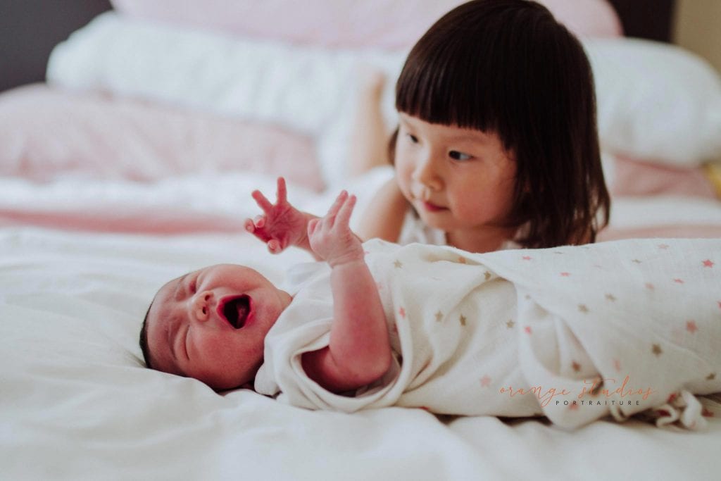 newborn baby with elder sister during fresh 48 photoshoot at home