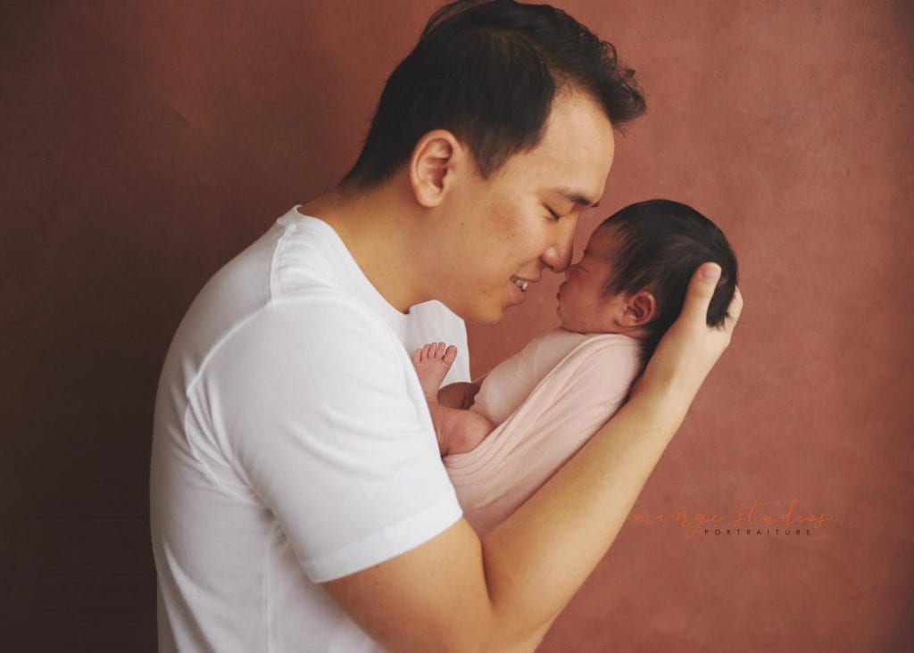 dad doing a nose to nose with his newborn baby girl in singapore home natural lighting