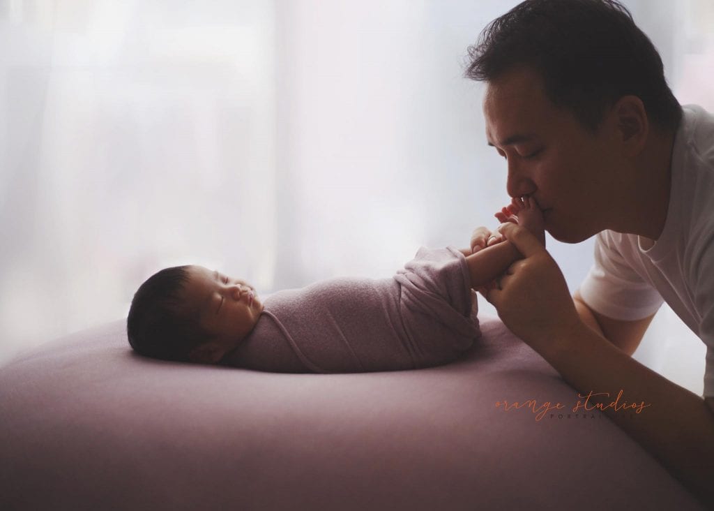 dad kissing little feet of his newborn baby girl