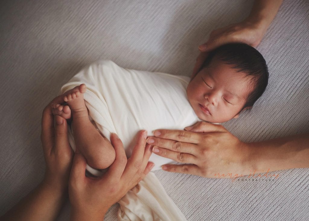 parents' hands on newborn baby