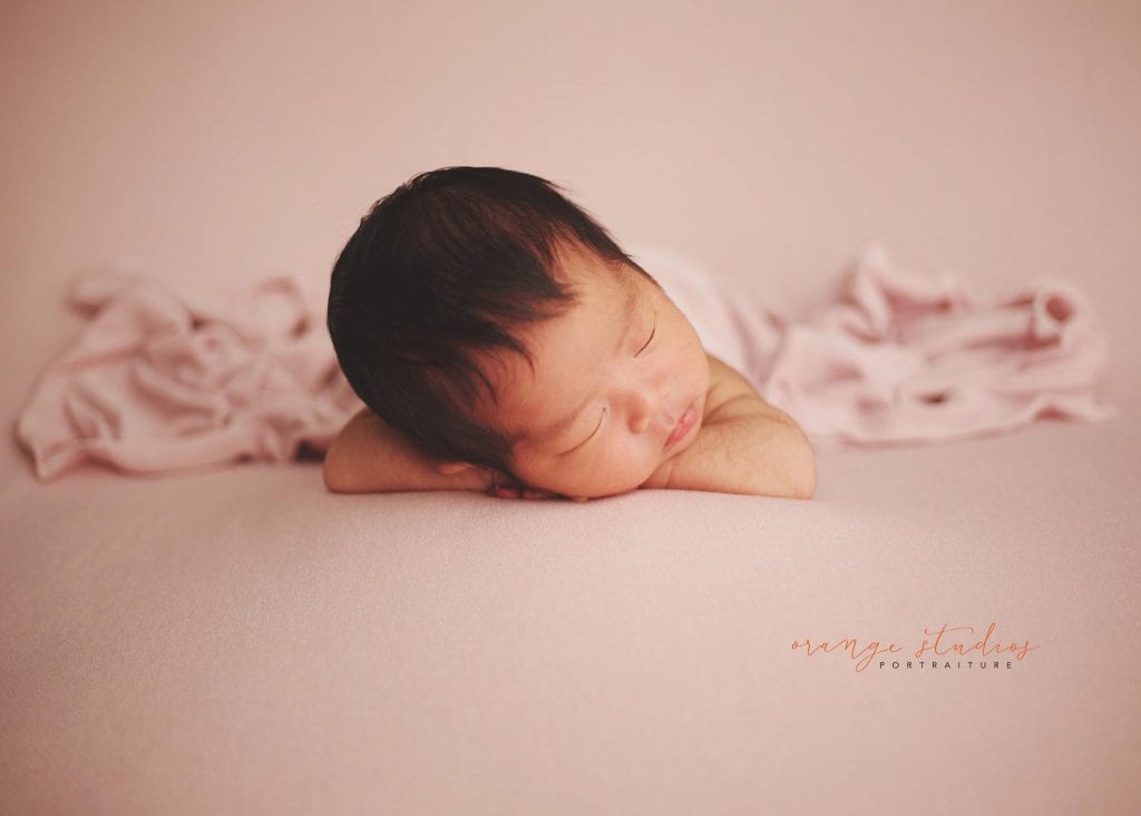 cute newborn baby resting her head on her hands