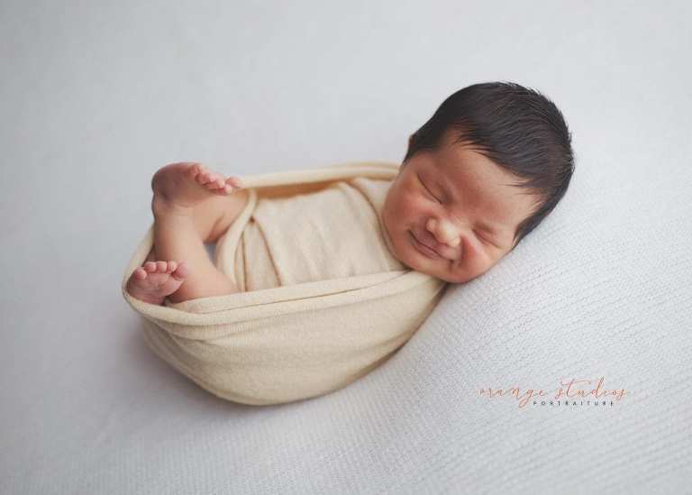 smiling 8 days old baby boy newborn portraits in singapore studio