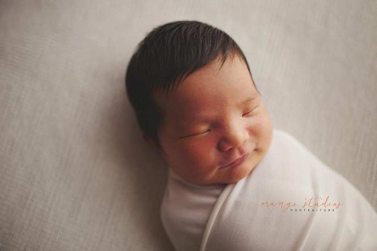 smiling 8 days old baby boy newborn portraits in singapore studio