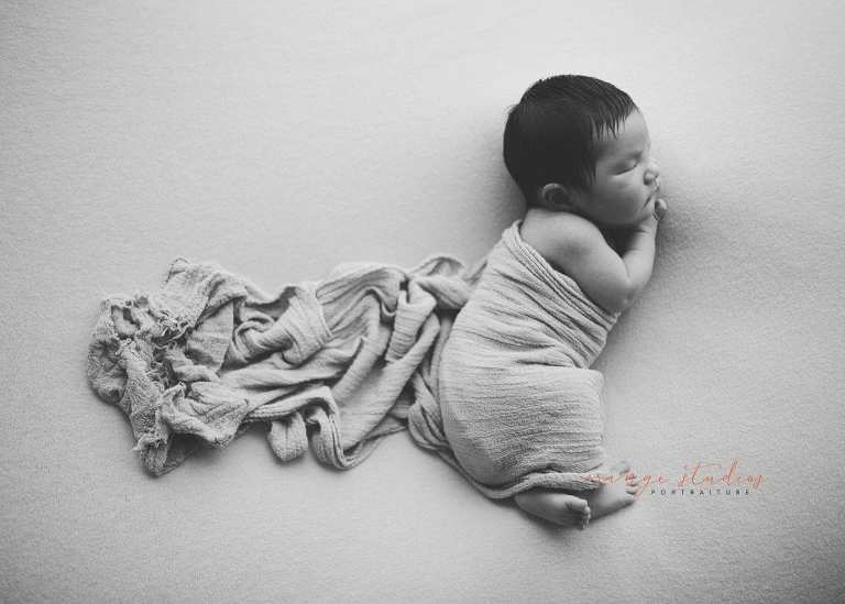8 days old baby boy side pose black and white newborn portraits in singapore studio