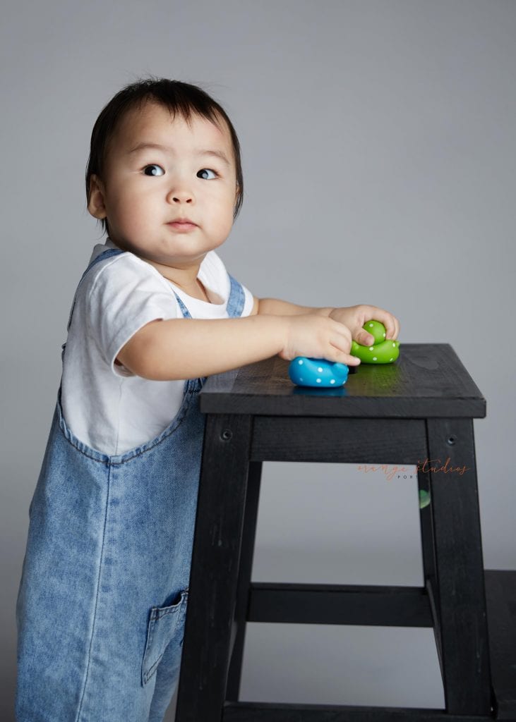 1 year old baby boy standing with support portraits in singapore studio