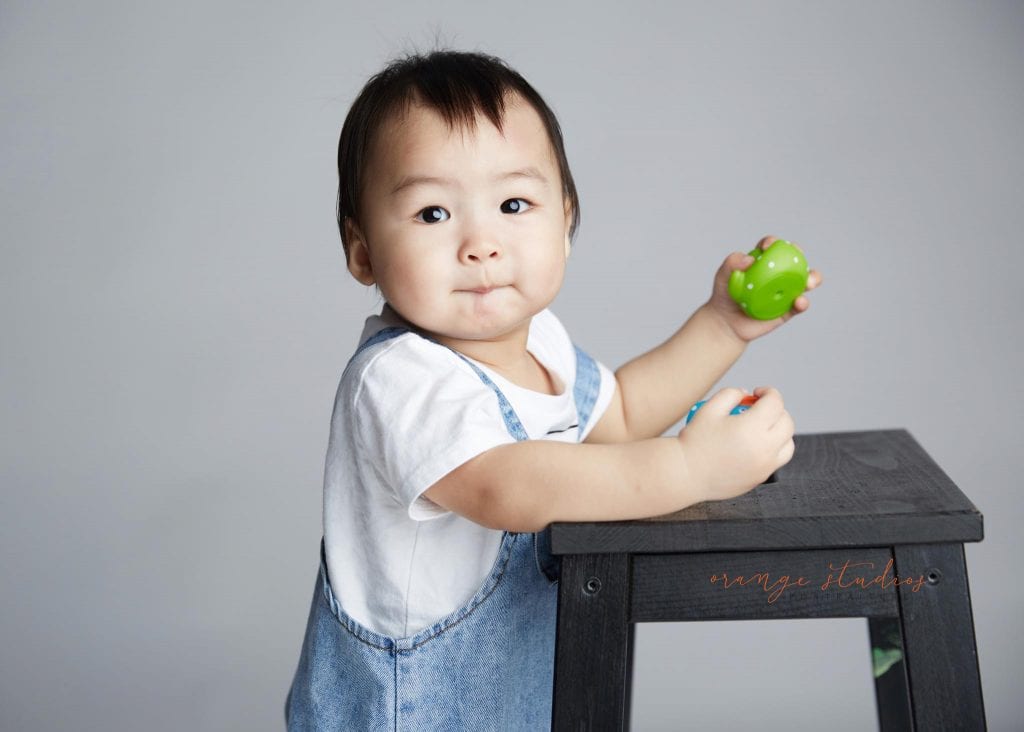 1 year old baby boy standing with support portraits in singapore studio
