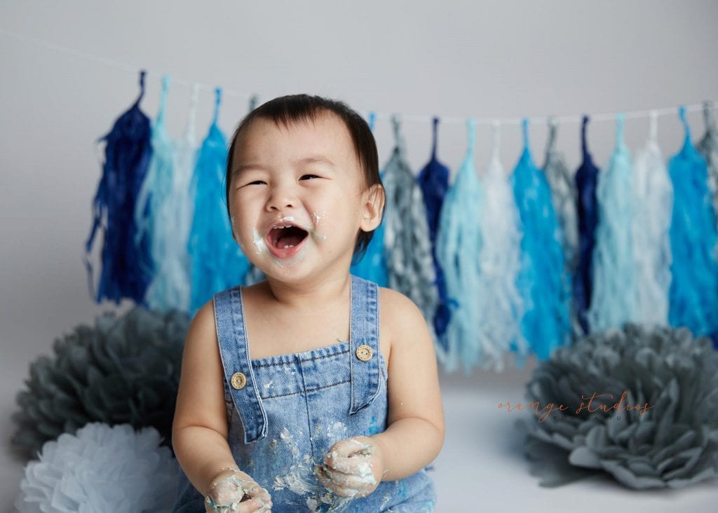 happy 1 year old baby boy cake smash portraits in singapore studio