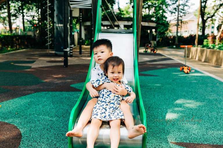 brother and sister playing on slide in singapore outdoors