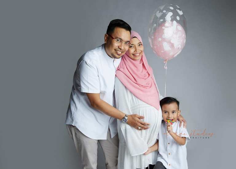 maternity portraits with family holding gender reveal balloon in singapore studio
