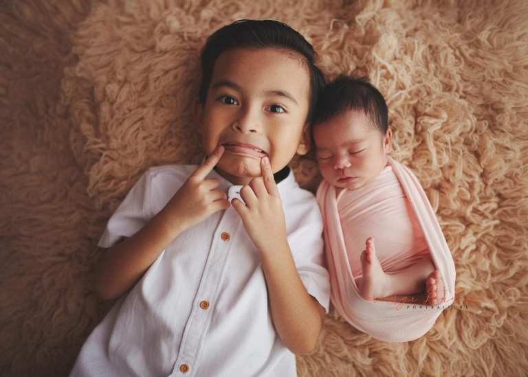 cheeky elder brother with newborn baby sister portraits in singapore studio
