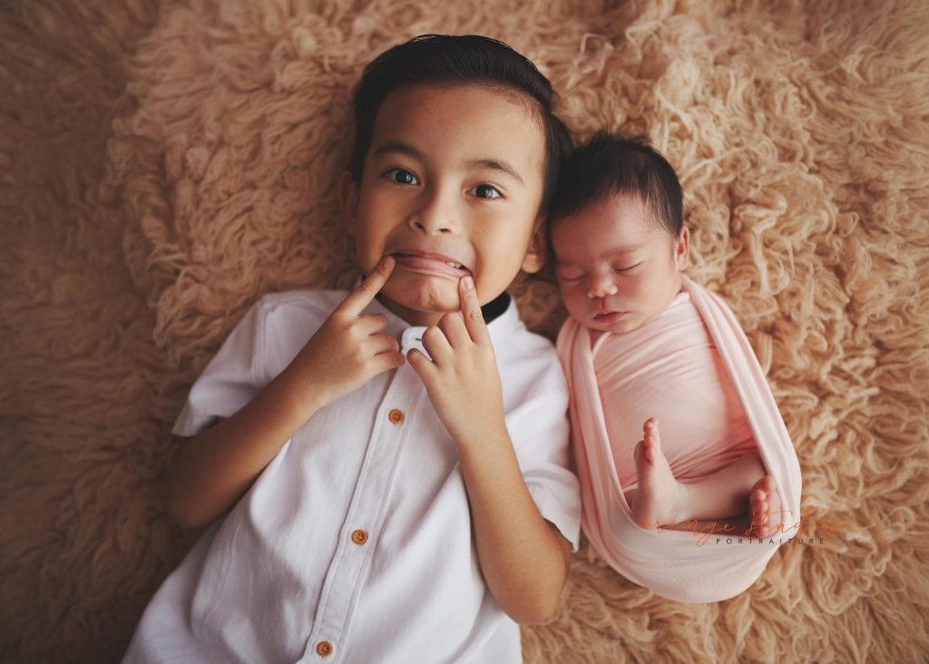cheeky elder brother with newborn baby sister portraits in singapore studio