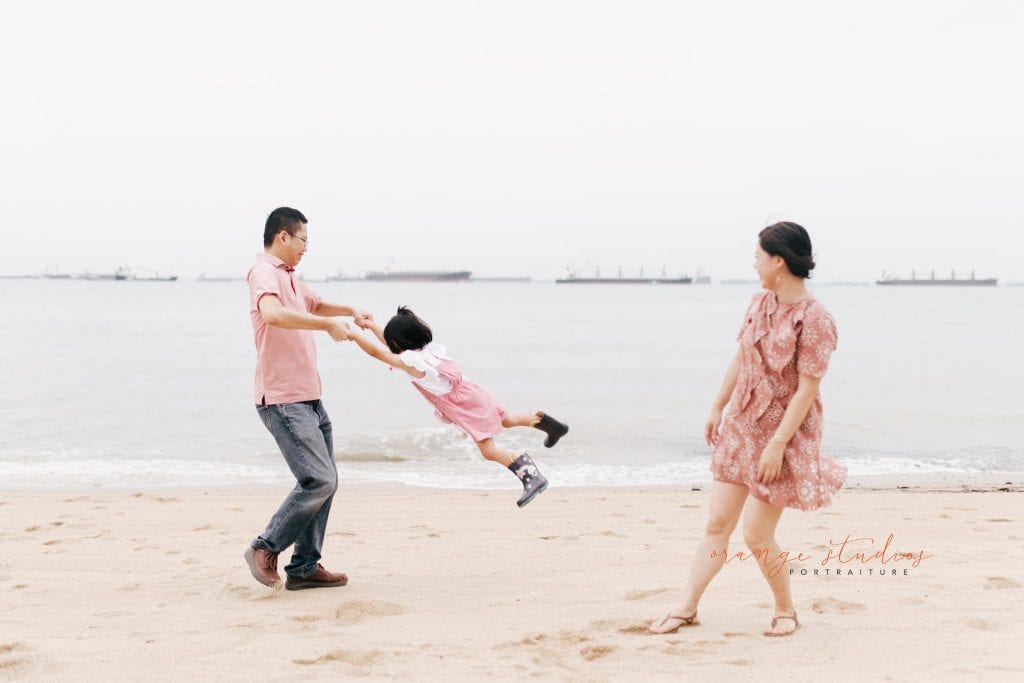 dad swinging girl outdoor family portraits at singapore beach