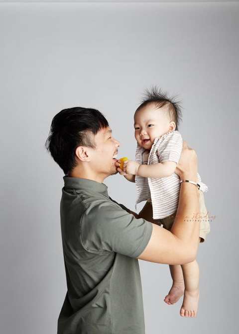 smiling 1 year old baby boy with dad family portraits in singapore studio