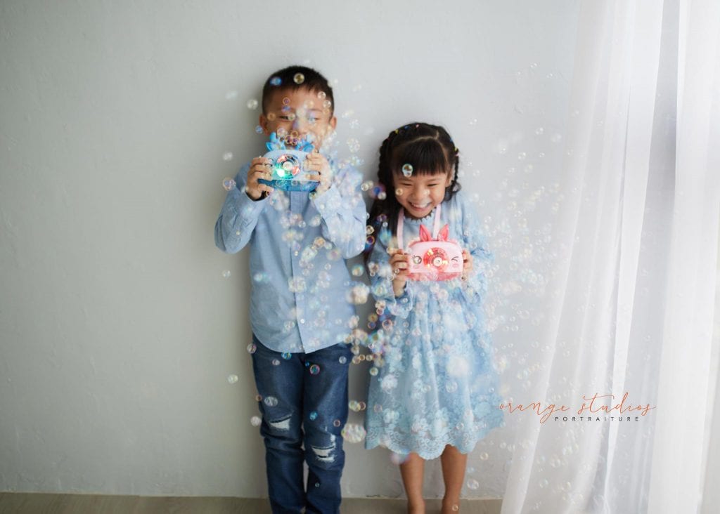siblings playing with bubbles in singapore natural light studio