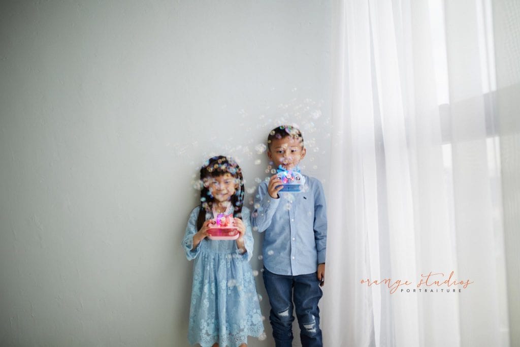 siblings playing with bubbles in singapore natural light studio
