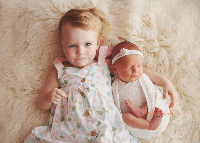 sibling with baby laying down posing at orange studios